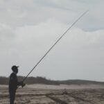 Pescador con caña de spinning junto al mar