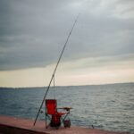 Caña de surfcasting y silla en la orilla